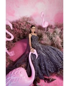 a woman in a dress sitting on a pink flamingo