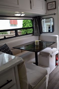 the inside of a camper with a dinning table and bench next to it