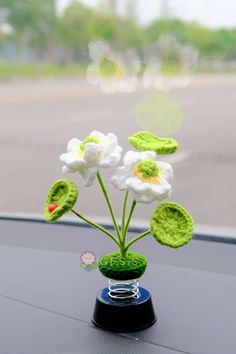 there is a crocheted flower in the vase on the car's dashboard