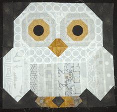 an owl made out of scrap paper on a piece of black and white fabric with circles around the eyes