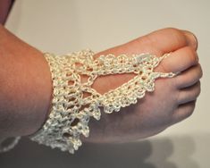 a close up of a person's arm wearing a white crochet bracelet