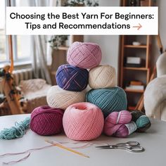 several balls of yarn sitting on top of a table next to scissors and knitting needles