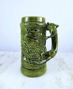 a green glass mug with an animal design on it