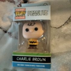 the peanuts character is in its box on the bed with it's head turned to look like charlie brown