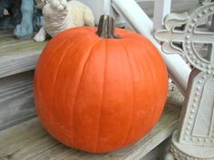 an orange pumpkin sitting on the steps next to a cat figurine and a cross