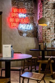 a restaurant with neon signs on the wall and wooden chairs in front of it,