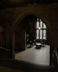 an arched doorway leads into a dimly lit room with tables and chairs on the floor