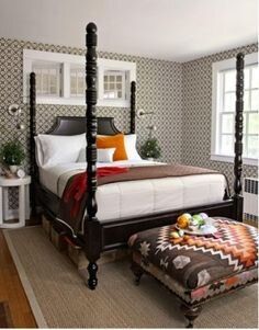 a bedroom with a four post bed and ottoman