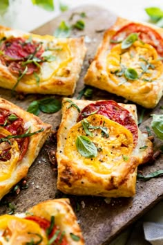 small square pizzas with tomatoes and herbs on a cutting board, ready to be eaten