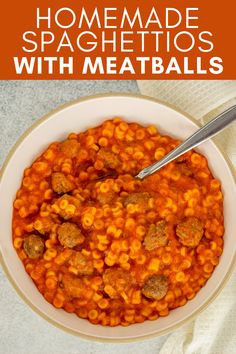 a bowl filled with pasta and meatballs on top of a white cloth next to a spoon