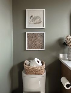 a white toilet sitting in a bathroom next to a wall with pictures on the wall