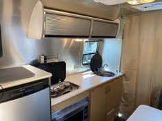 a kitchen with a sink, stove and refrigerator in it next to a curtained window