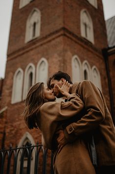 a man and woman kissing in front of a church