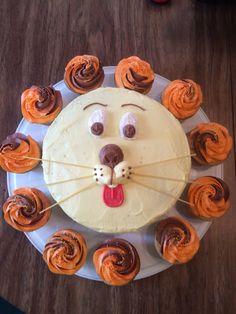 a cake with icing and cupcakes in the shape of a lion's head