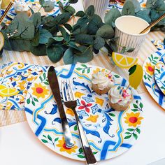 a plate with cupcakes and lemon slices on it next to some greenery