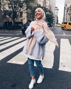 a woman wearing a hijab crossing the street