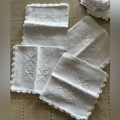 four white embroidered napkins on a table