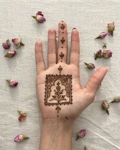 a person's hand with a henna tattoo on it and flowers scattered around