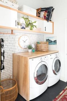 a washer and dryer sitting in a room next to a shelf with clocks on it