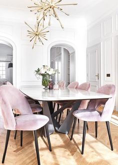 a dining room table with purple chairs and pictures on the wall behind it in an elegant style