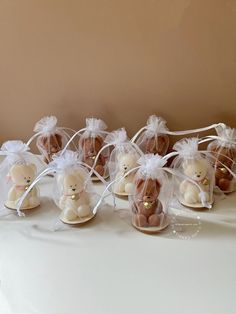 several small teddy bears in clear bags on a white table cloth covered with organ string