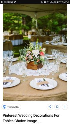 the table is set with white plates, silverware and flowers in a wooden box