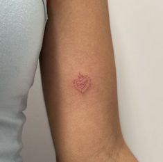 a woman's arm with a small heart tattoo on the left side of her arm