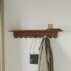 a coat rack with two coats hanging from it's sides and a purse on the other side