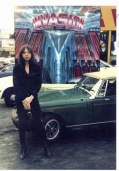 a woman standing next to a green car in front of a sign that says masion