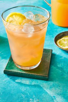 two glasses filled with orange juice and lemon slices on top of coasters next to each other