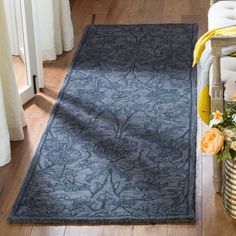 a large blue rug sitting on top of a wooden floor next to a vase filled with flowers