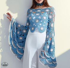 a woman wearing a blue crochet top and white pants with pearls on it