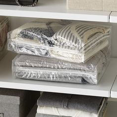 several folded clothes are sitting on top of each other in a closet with white shelving