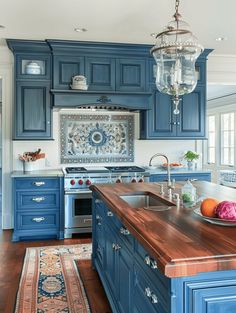 a kitchen with blue cabinets and an island in front of a stove top oven next to a sink