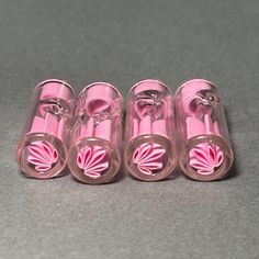 four pink plastic tubes with flower designs on them