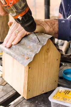 a man using a drill to attach a piece of wood on top of a box