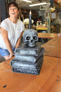 a man standing next to a stack of books with a skull on it