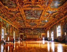 an ornately decorated room with many paintings on the walls and ceiling, along with people walking around