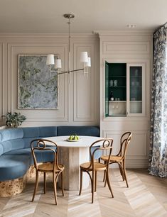 a living room with blue couches and chairs around a white table in the center