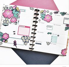 an open planner book on top of a pink and white envelope with floral designs in the pages