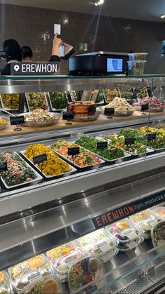 a display case filled with lots of different types of salads and condiments