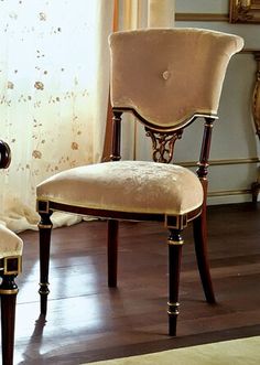 two chairs sitting next to each other on top of a hard wood floor in front of a window