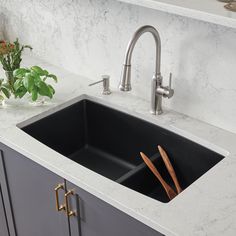 a kitchen sink with two wooden utensils in the bottom and one on the side