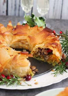 a plate topped with a pastry covered in nuts and other toppings next to wine glasses