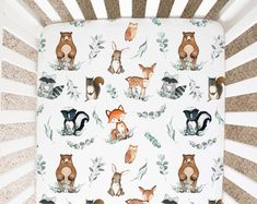 a baby crib with woodland animals on it's bed sheet and pillowcase