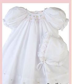 Adorable Petit Ami white batiste daygown in Newborn size. Sweet bishop dress with smocking at the neckline with tiny hand embroidered rosettes in pink, yellow and blue. Smocking continues on the cuffs featuring raglan sleeves. Fine detail is shown at the hem with additional matching embroidered rosettes in colors of pink, yellow and blue. Button back for easy dressing. White bonnet with ruffle edge and tiny rosette on each side complete this set. Absolutely Precious! 65% Polyester, 35% Cotton. 1 Spring Baptism Dress With Smock Detail, Spring Baptism Dress With Smocked Bodice, Fitted Smock Baptism Dress For Spring, White Baptism Dress With Smocked Back For Spring, White Spring Baptism Dress With Smocked Back, Smocking Baby, White Smocked Dress, Embroidery Design Pattern, Smocked Bishop Dress