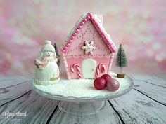 a pink and white christmas cake on a platter