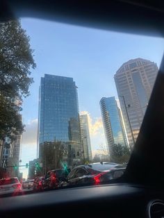 cars driving down the street in front of tall buildings