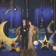 a man and woman standing in front of a stage set with stars and moon decorations