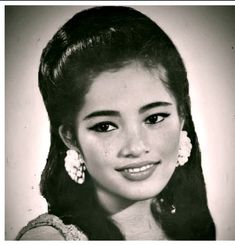 an old black and white photo of a woman with long dark hair wearing large earrings